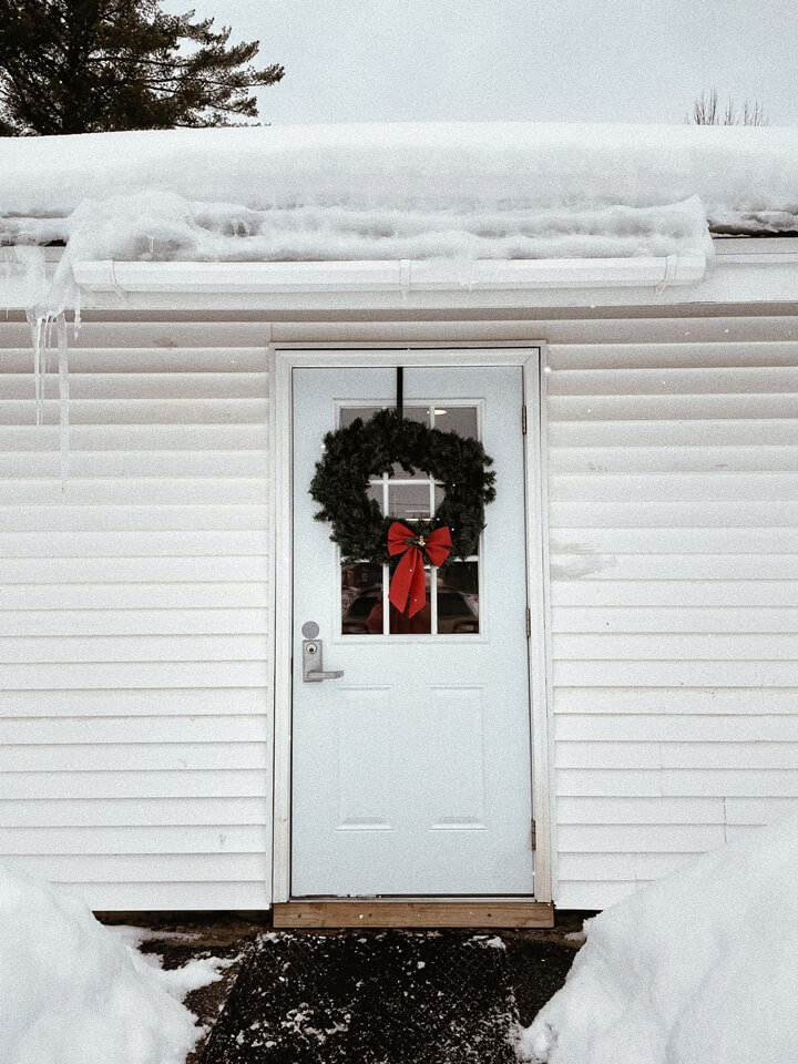 Front entrance of Adirondack Alliance Church in winter with a welcoming wreath on the door